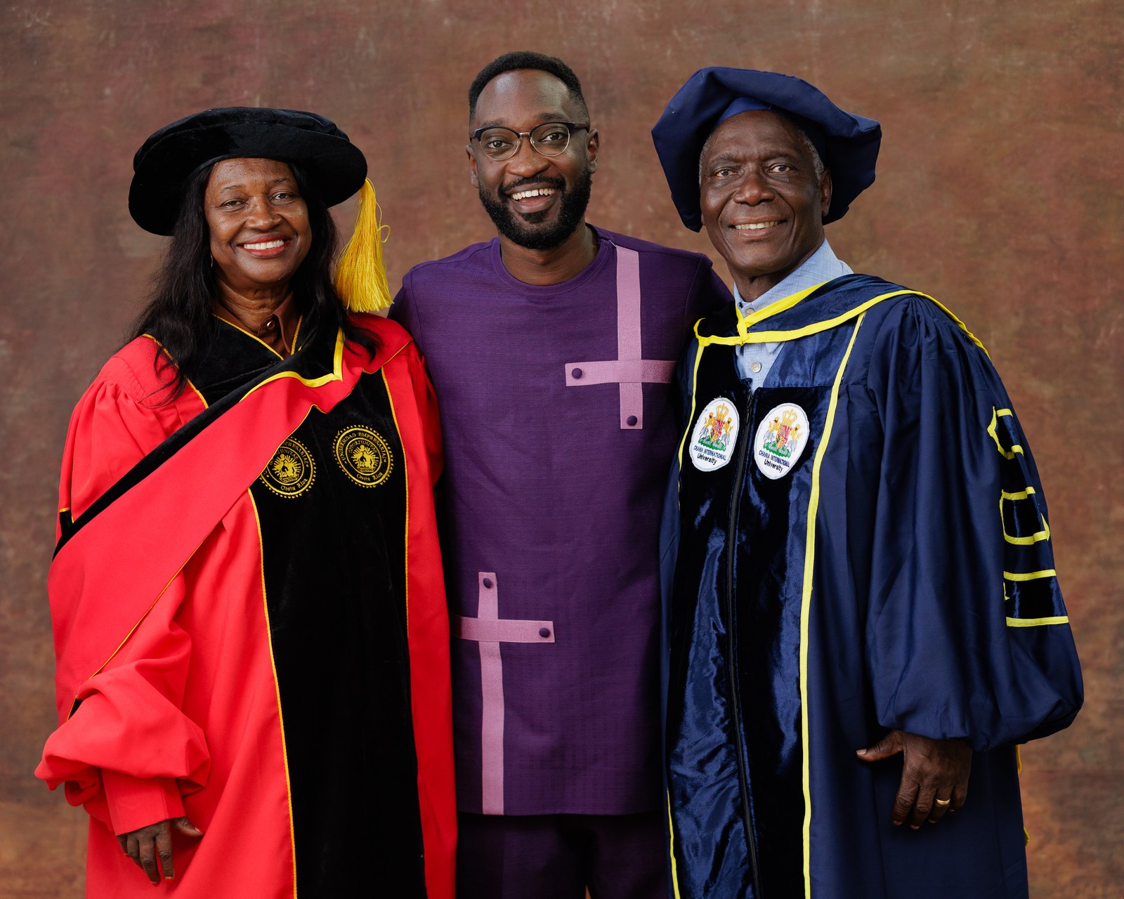 Three people in doctoral academic regalia photographed together at a graduation ceremony